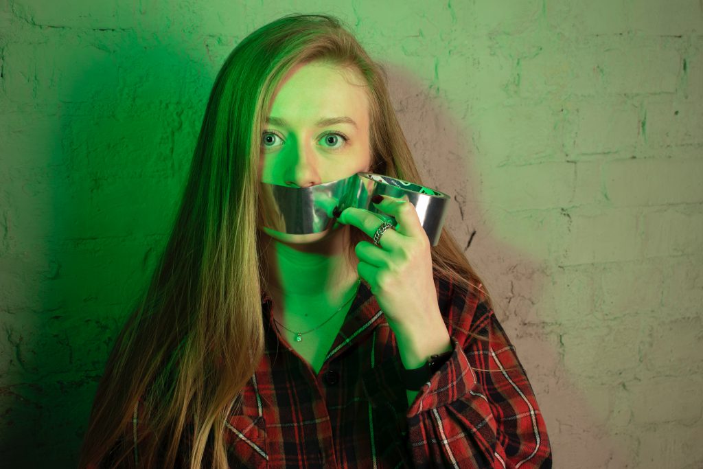 woman with tape over her mouth who is struggling to speak her new language
