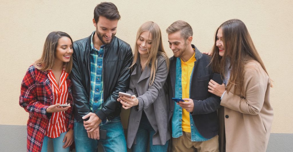 friends standing around looking at ios apps