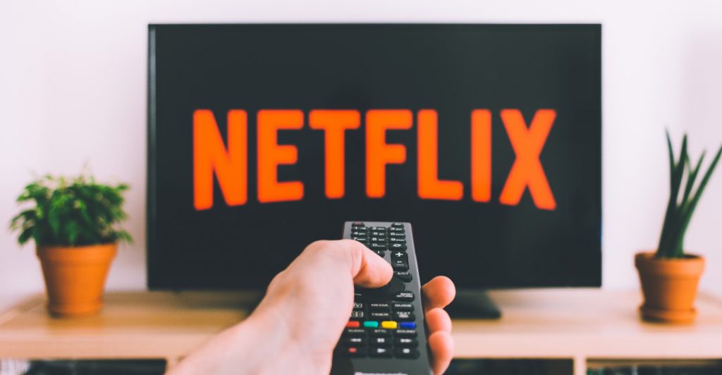 view of netflix screen with a hand holding a remote ready to watch spanish movies