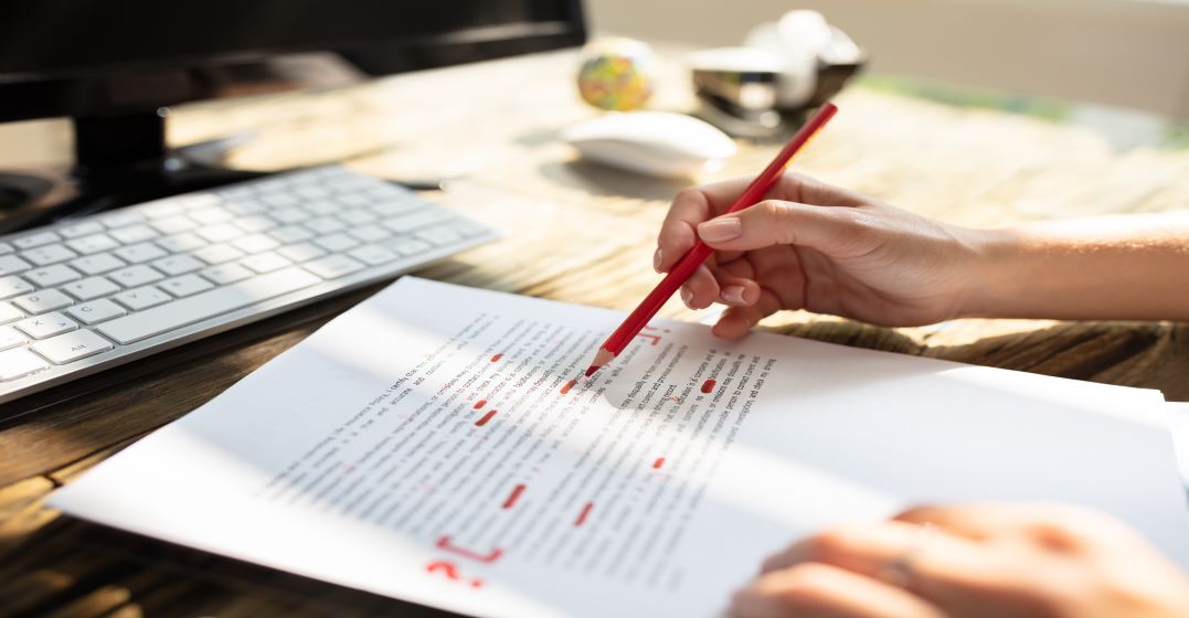 Text on paper being corrected with a red pencil