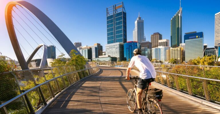 Cyclist in front of Perth financial district with a good average Australian salary