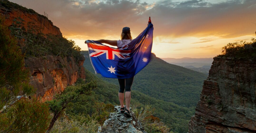 Australia vs. New Zealand: Girl in a national park hoöding a flag of Australia