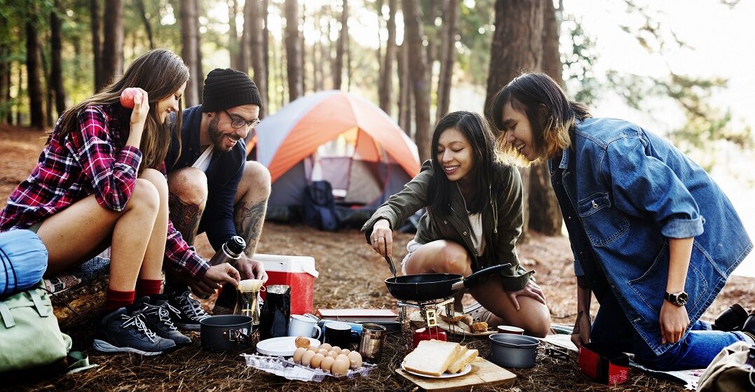 Friends sitting around a campfire practicing camping vocabulary