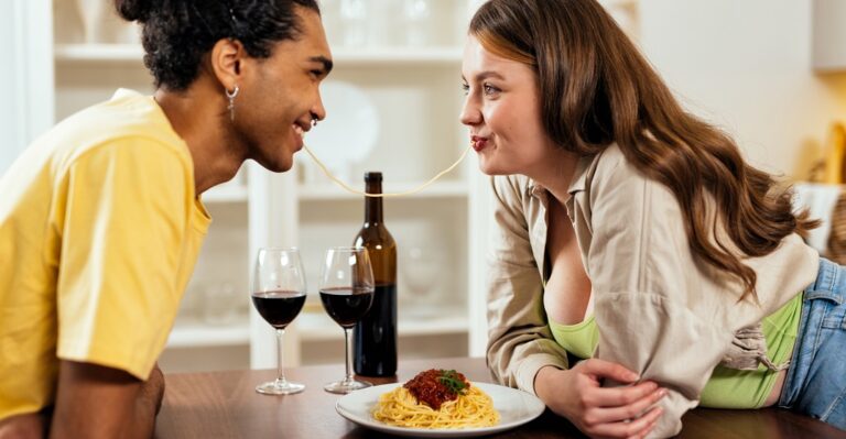 One european stereotype about italians eating pasta. A boy and a girl holding both ends of a spaghetti in their mouth.