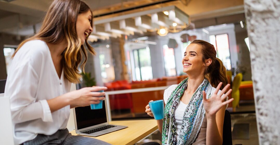 Two female friends chatting over coffee using sentence starters and filler words in Spanish