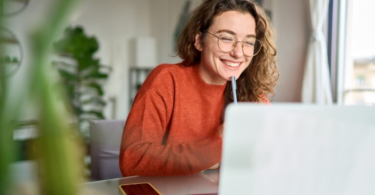 Happy woman at her laptop taking an online language class instead of offline