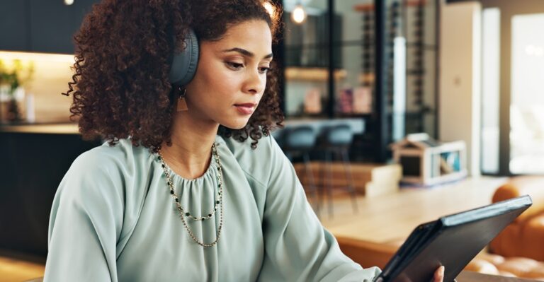 Woman with headphones researching the best websites to learn English at her tablet