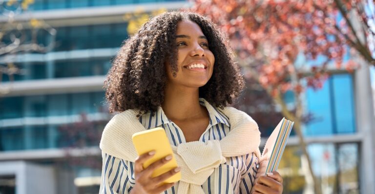 Smiling woman holding her phone to research the best websites to learn Spanish