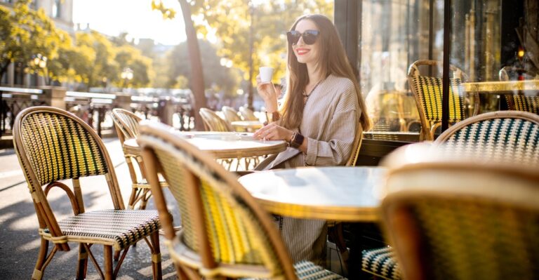 Young woman in traditional French café drinking coffee